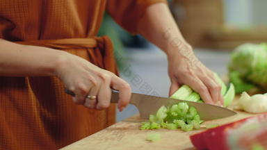女人手切芹菜切割董事会家庭主妇烹饪新鲜的蔬菜